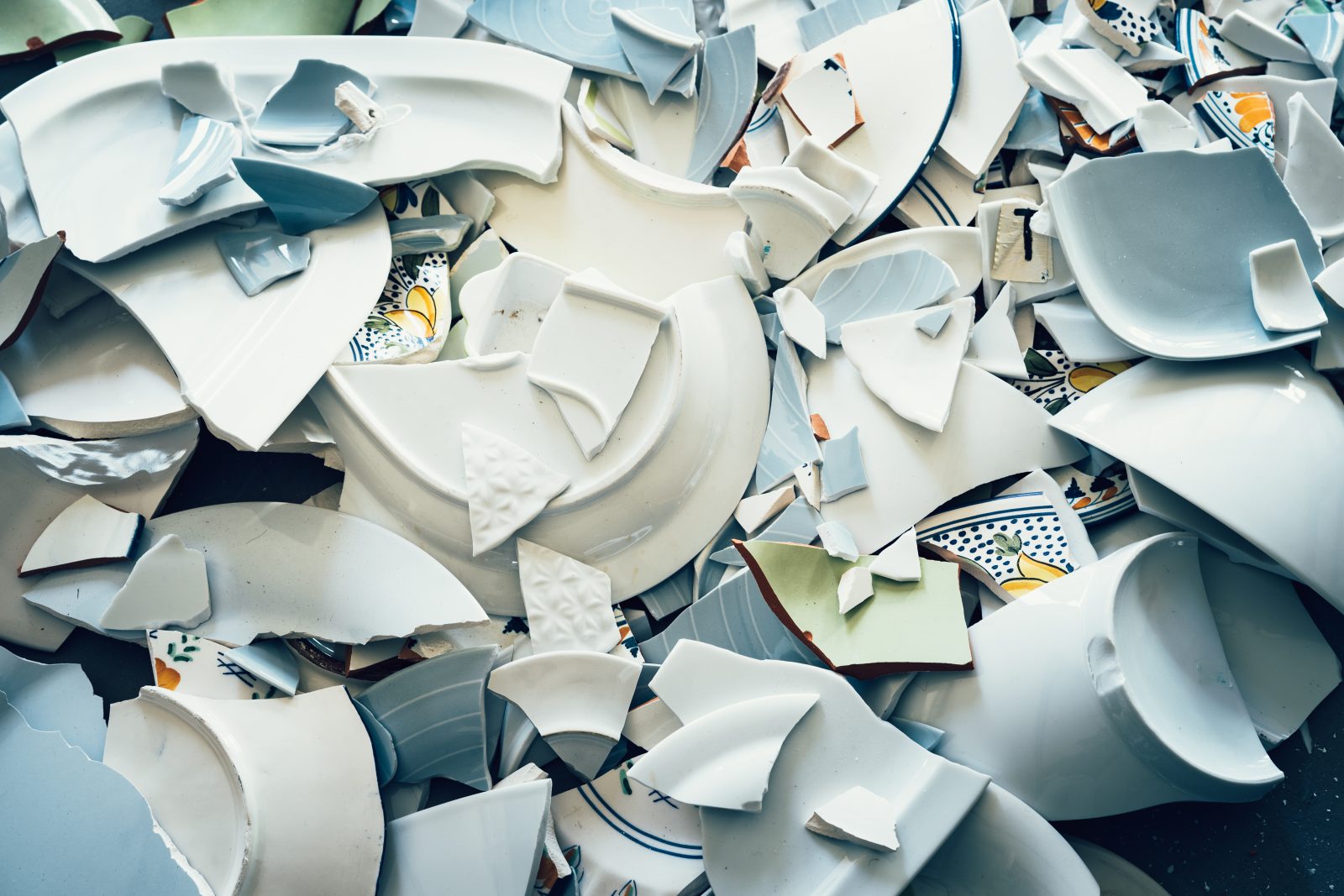 Shards of broken crockery ceramic plates cups and porcelain on the floor