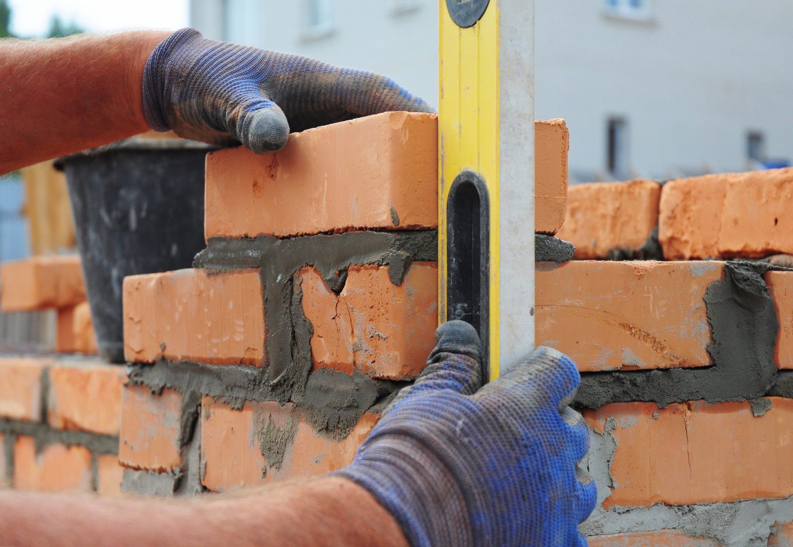 Bricklayer Using a Spirit Level to Check New Red Brick Wall Outdoor. Bricklaying Basics Masonry Techniques.